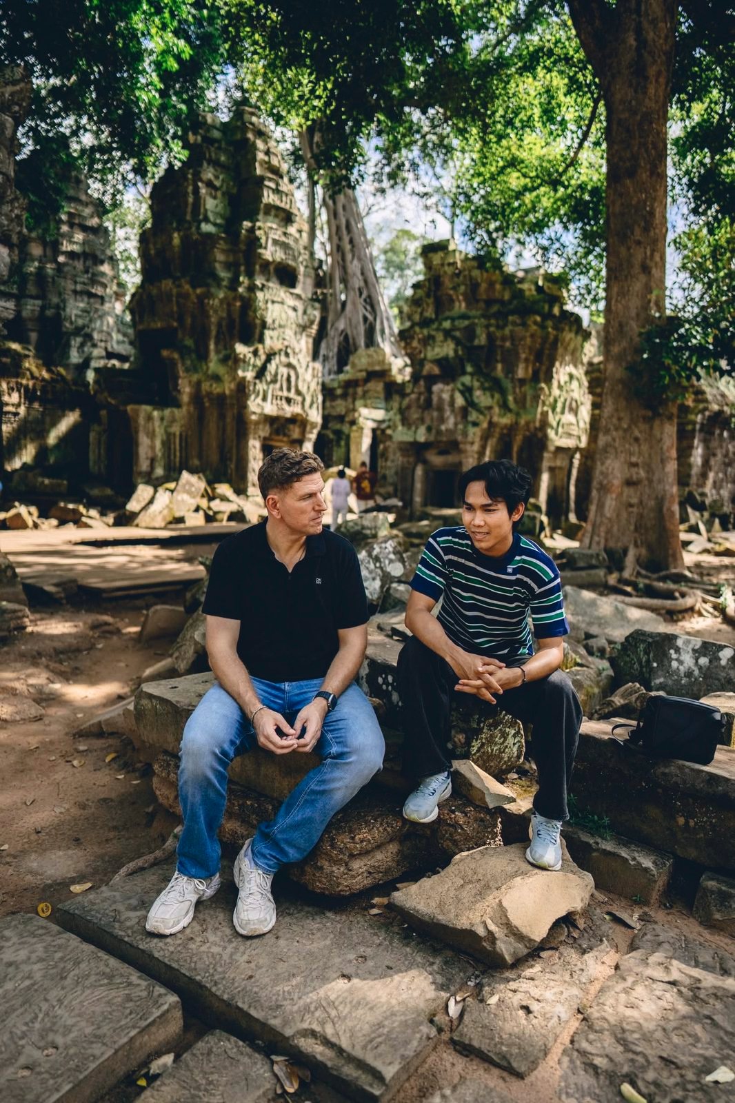 Two friends, one international and one Khmer, talking among temple stones