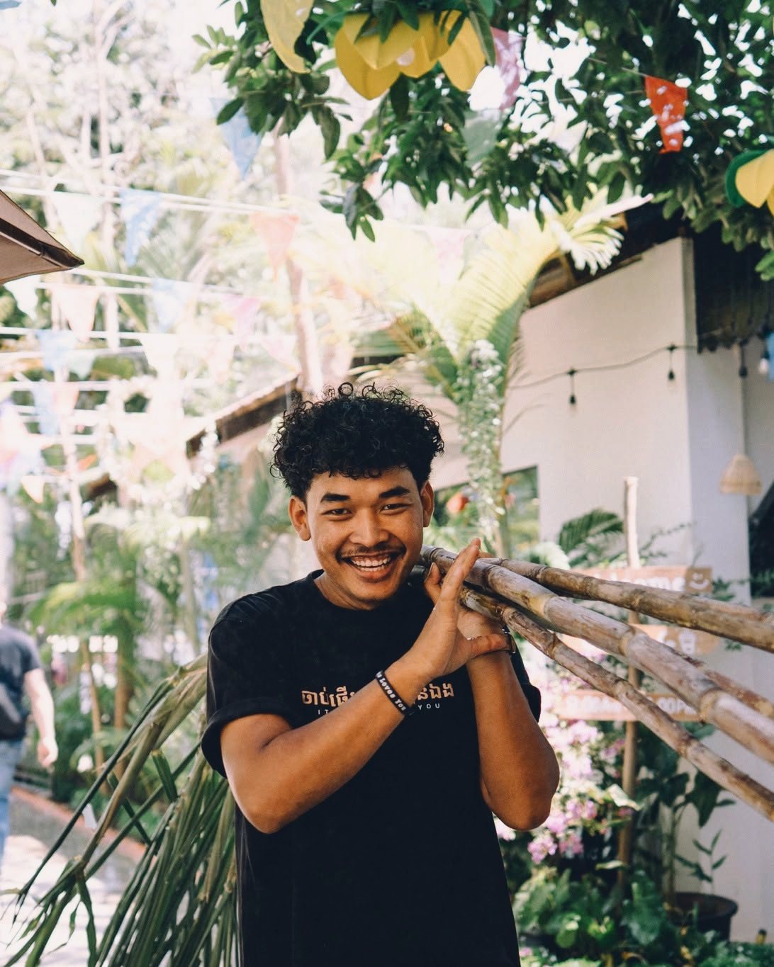 A young man carrying bamboo poles along a campus path
