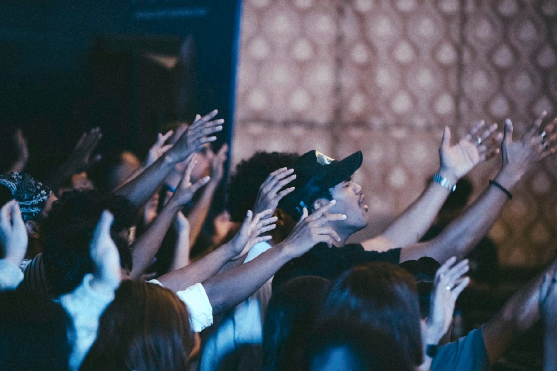 A room of young people worshipping with hands raised