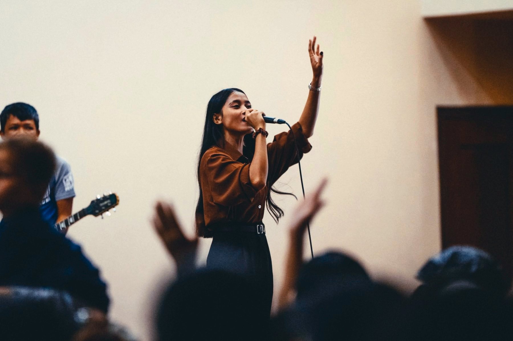 A worship leader singing with one hand raised